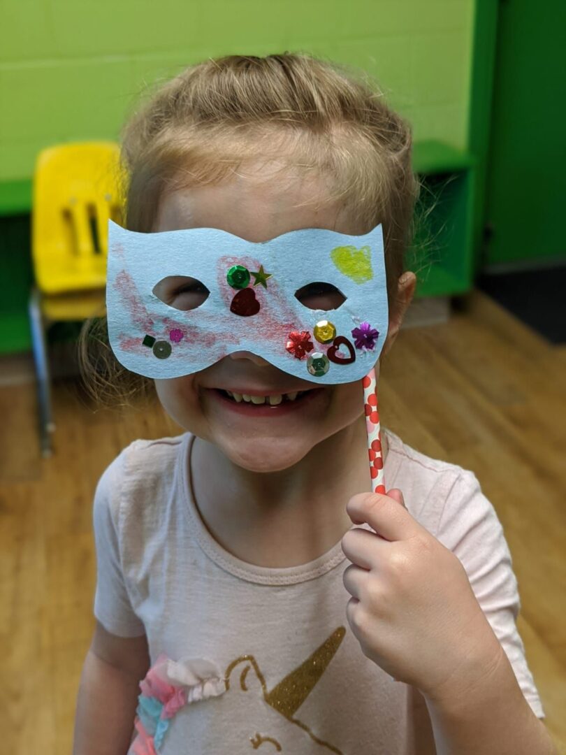 A young girl trying to wear a mask designed by her